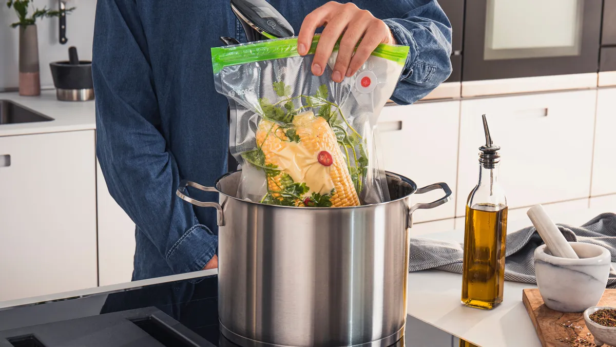 Un sac sous vide plein d'aliments est placé dans une casserole en vue d'être cuit sous vide.