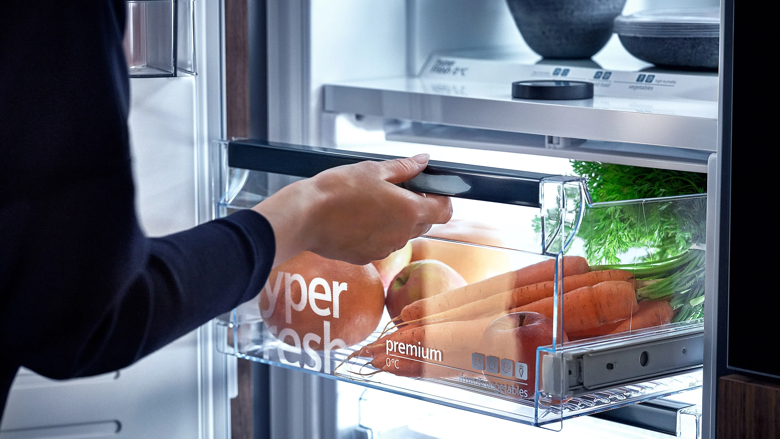 Open refrigerator with fresh produce, fruits, and packaged food items.