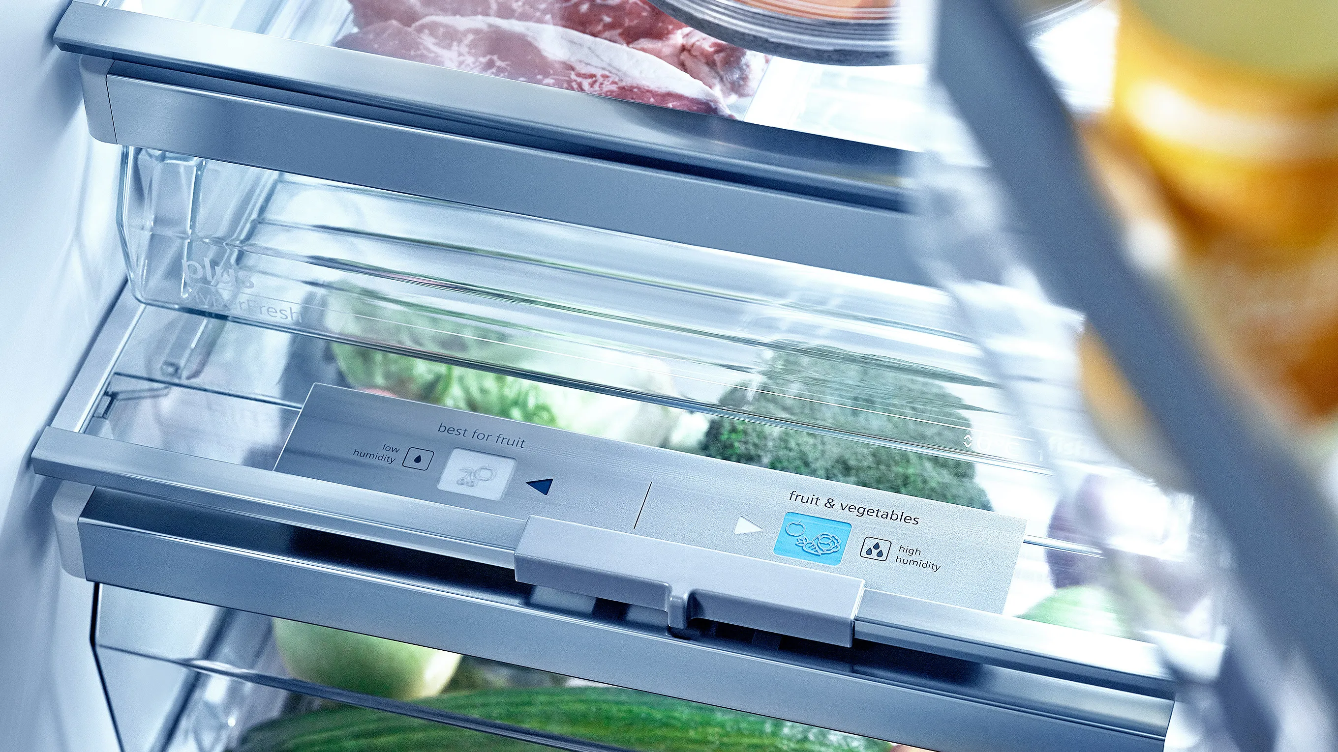 Open refrigerator with various food items, including meat, vegetables, and drinks.