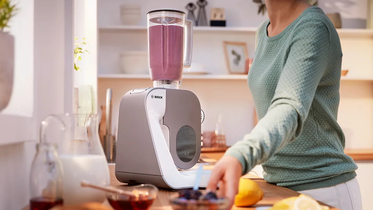 A person uses the blender attachment of the stand mixer to make a smoothie.