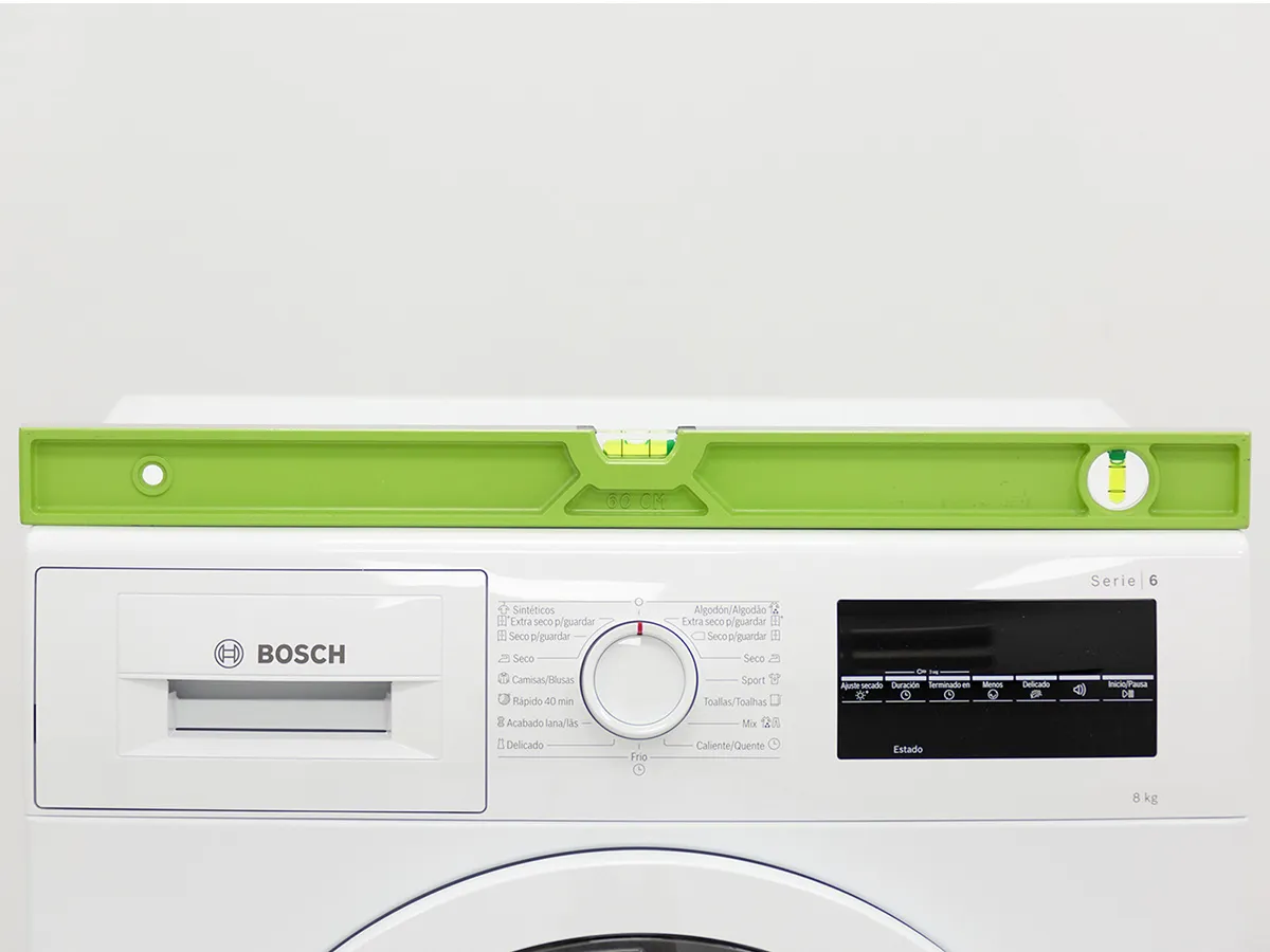Bright green level sitting on the front edge of a Bosch washing machine.