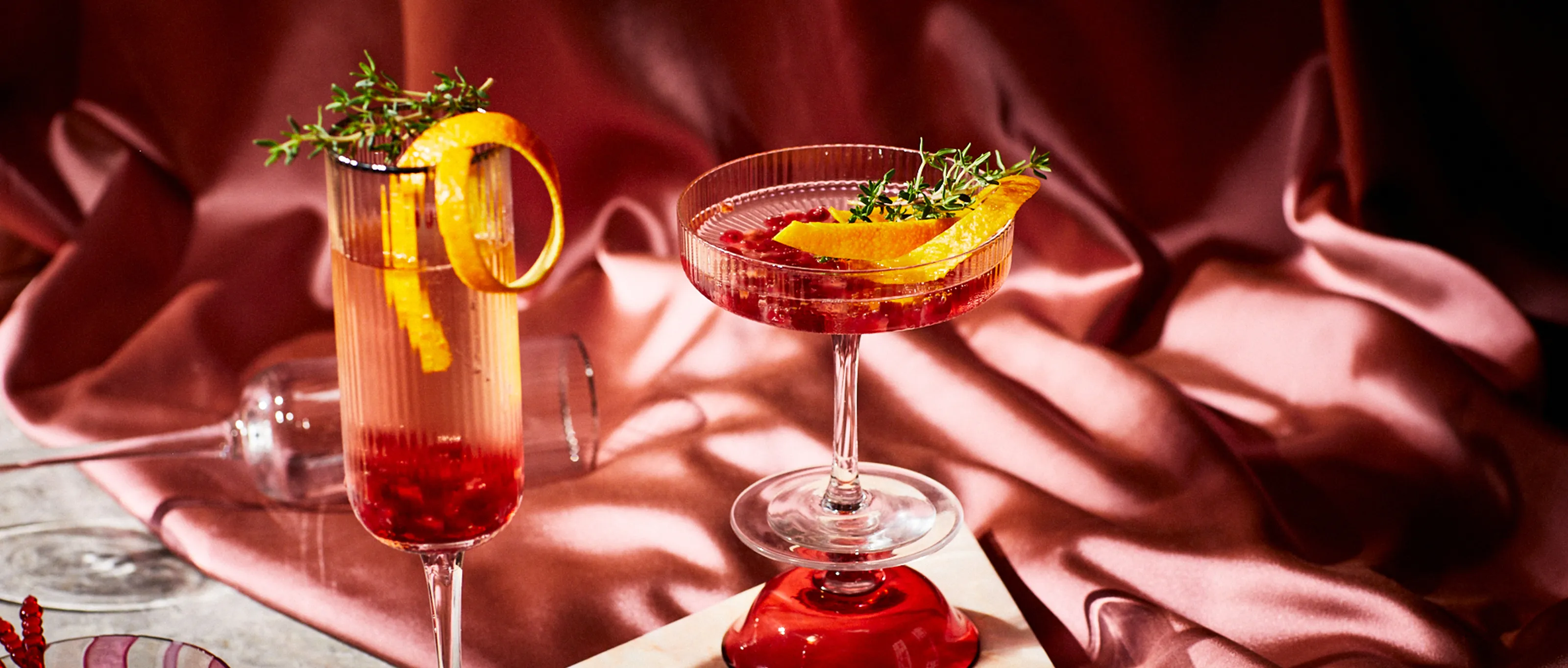Champagne cocktail in glass in front of pink background with shadows