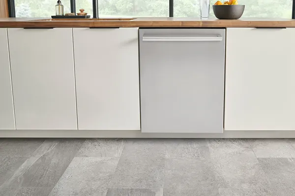 Modern kitchen with white cabinets, Bosch stainless steel dishwasher, and gray tile flooring.