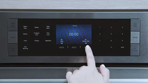 Hands operating Bosch digital control panel with display showing time.