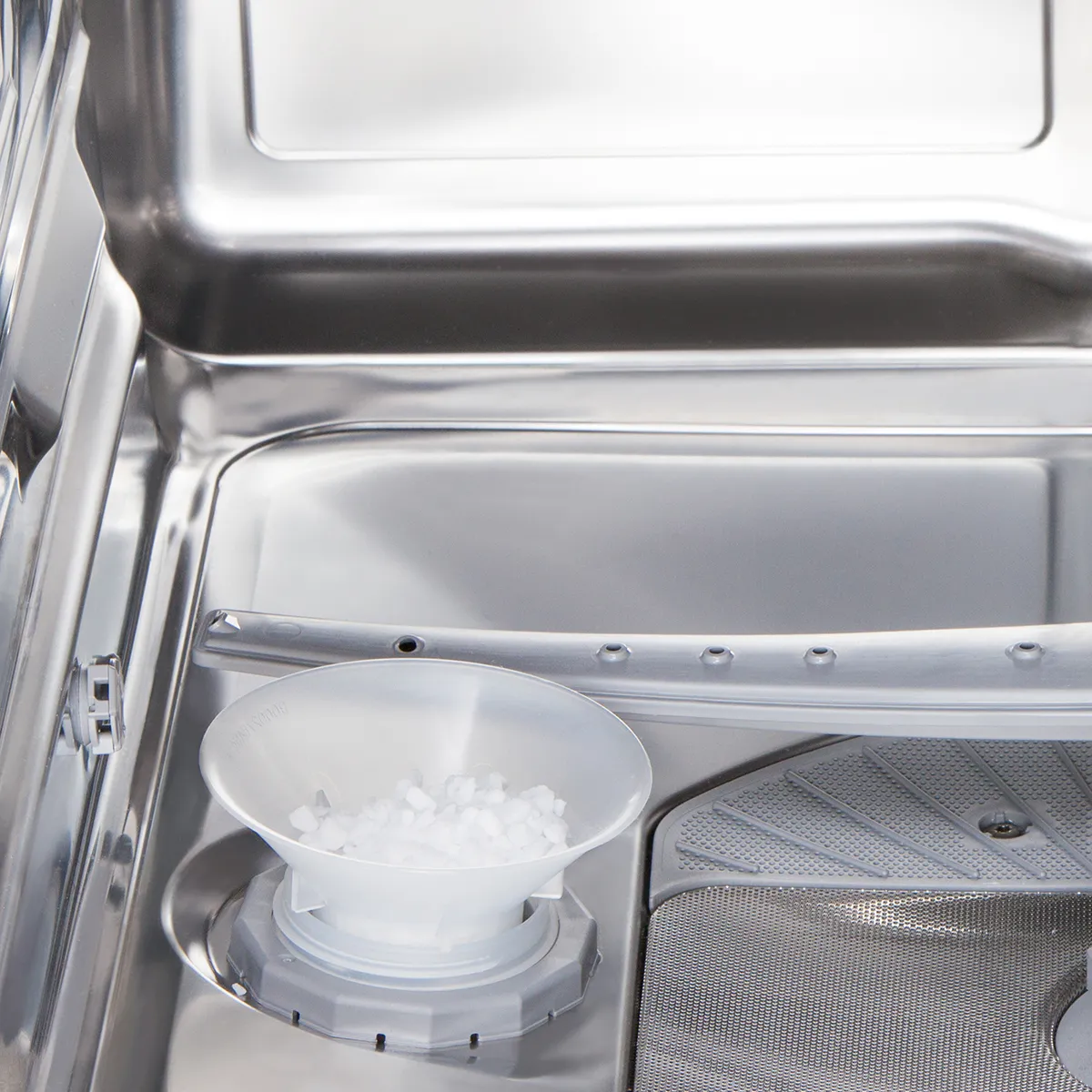 A close-up of the interior of a dishwasher shows a plastic cup filled with ice cubes placed on the bottom rack near the spray arm.