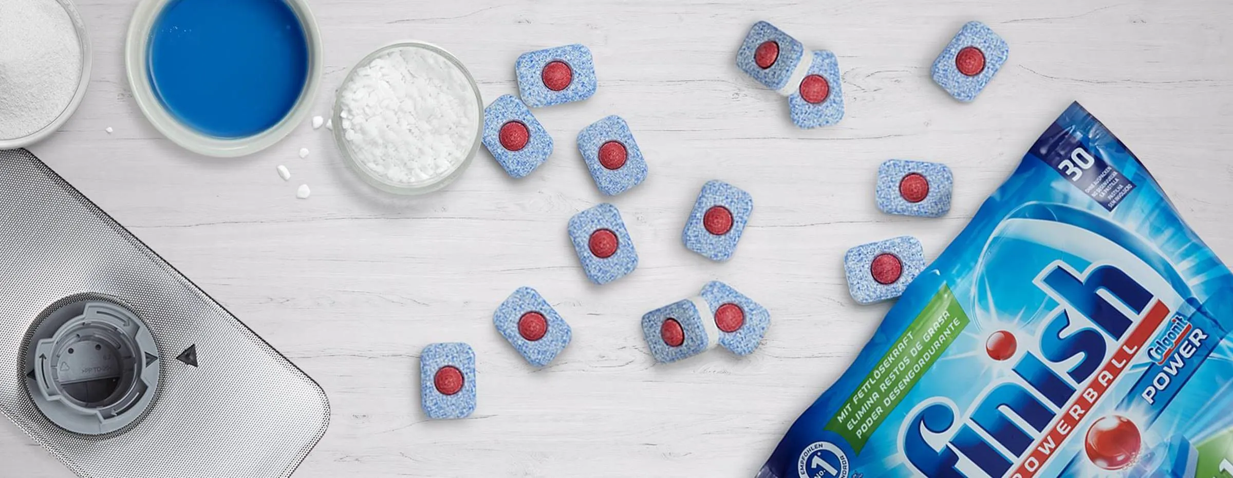 Laundry detergent, powder, and blue and red capsules on a white surface.