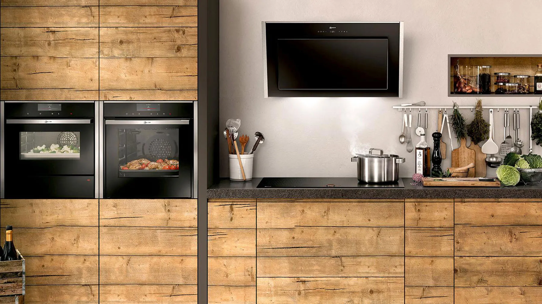 Rustic kitchen with wooden cabinets, built-in ovens, TV, and cooking utensils on shelves.