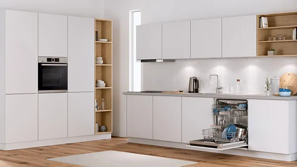 Modern kitchen with white cabinets, wooden shelves, and a dishwasher.