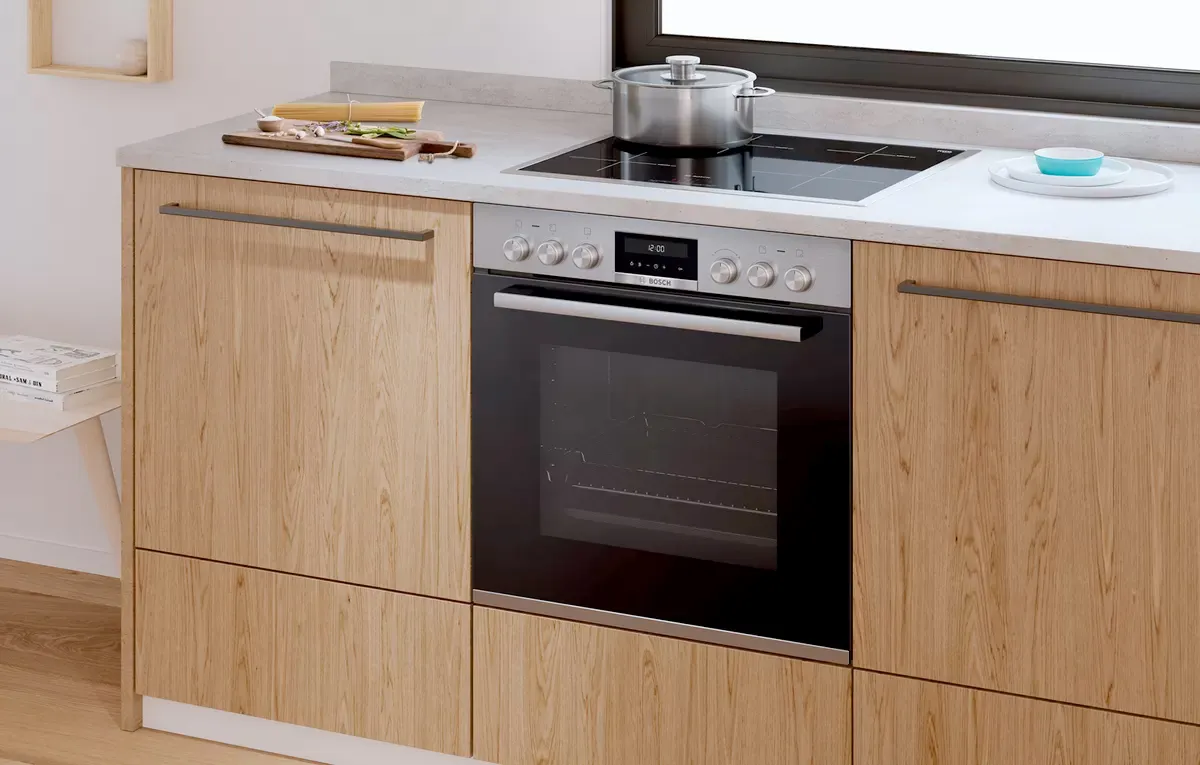A Bosch integrated oven with controls for the hob in a wooden kitchen.