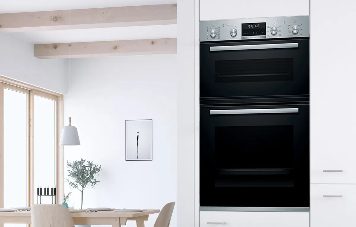 A Bosch double oven built into a wall in a modern white kitchen.