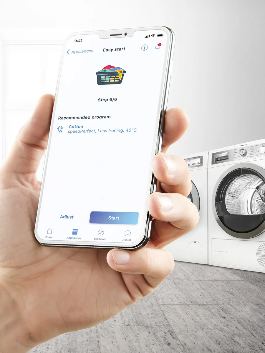 A hand holds a smartphone displaying the Bosch Home Connect app, showing the "Easy start" screen for a washing machine with a recommended program of "Cotton, speedPerfect, Less Ironing, 40°C."