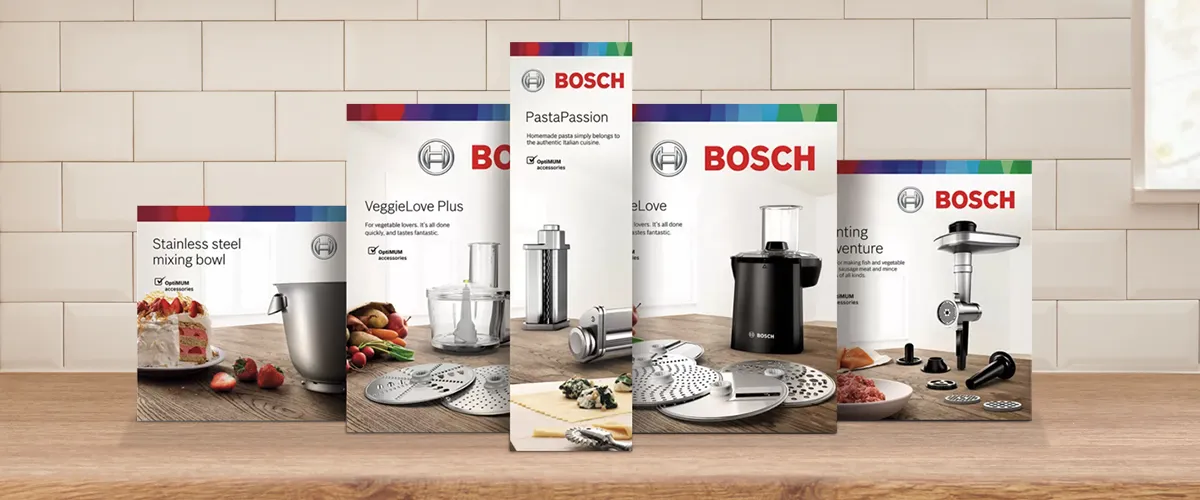 Stand mixer with PastaPassion attachment, with green pasta being fed through to make tagliatelle.