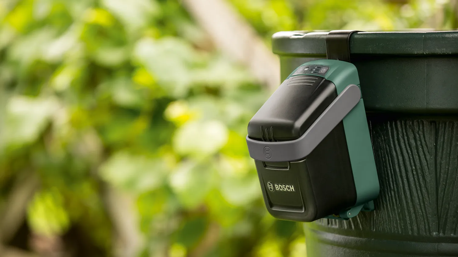 Partea de control si alimentare cu acumulator a unei pompe de grădină Bosch atașată unui recipient dintr-o grădină
