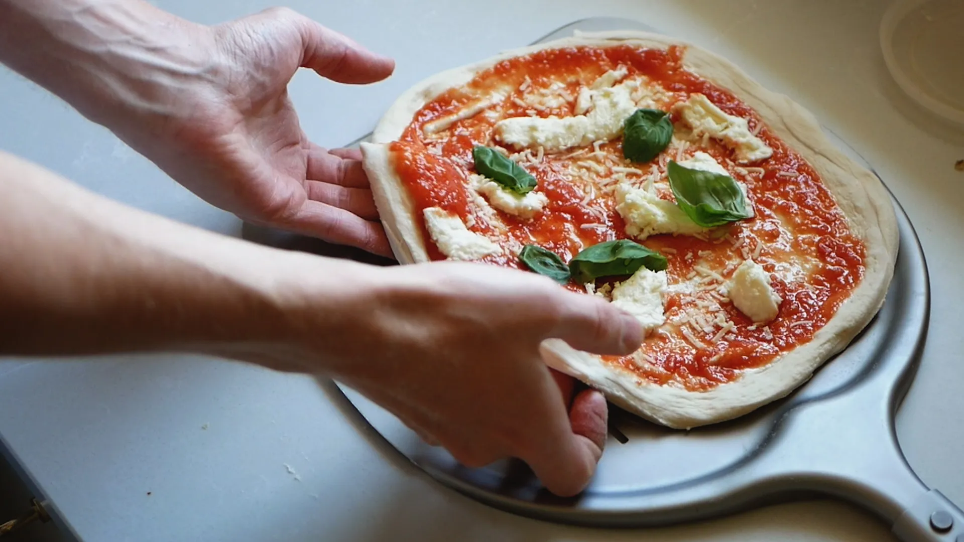 Steg 5 av att g\u00f6ra pizza med en nybakad pizza toppad med ost och basilika