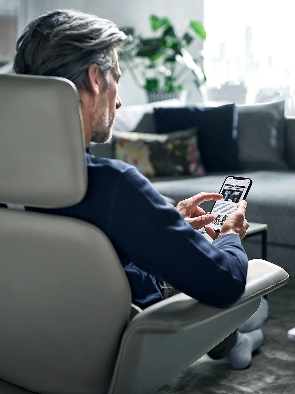 Man in suit using smartphone while sitting in armchair.