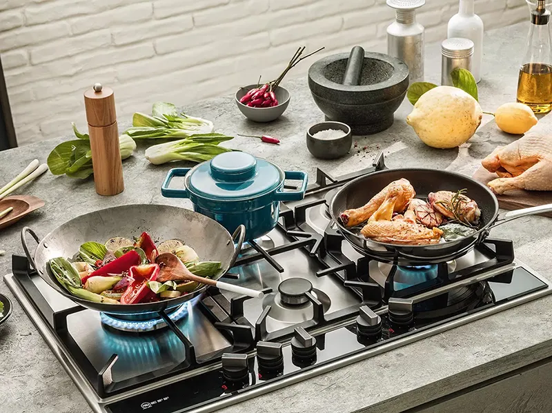 Cooking scene with various kitchen utensils, ingredients, and dishes on a stovetop.