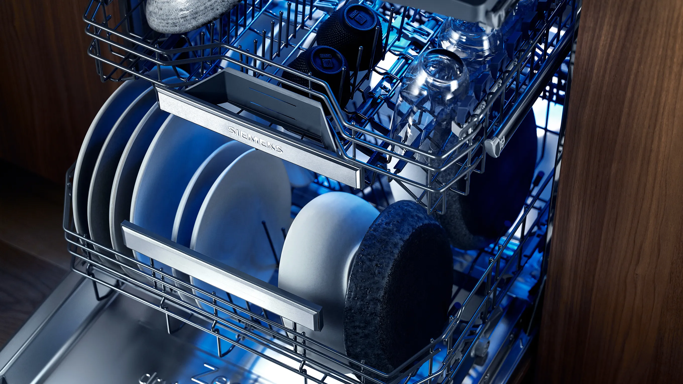 Lavastoviglie interno con piatti puliti, rack e illuminazione blu.