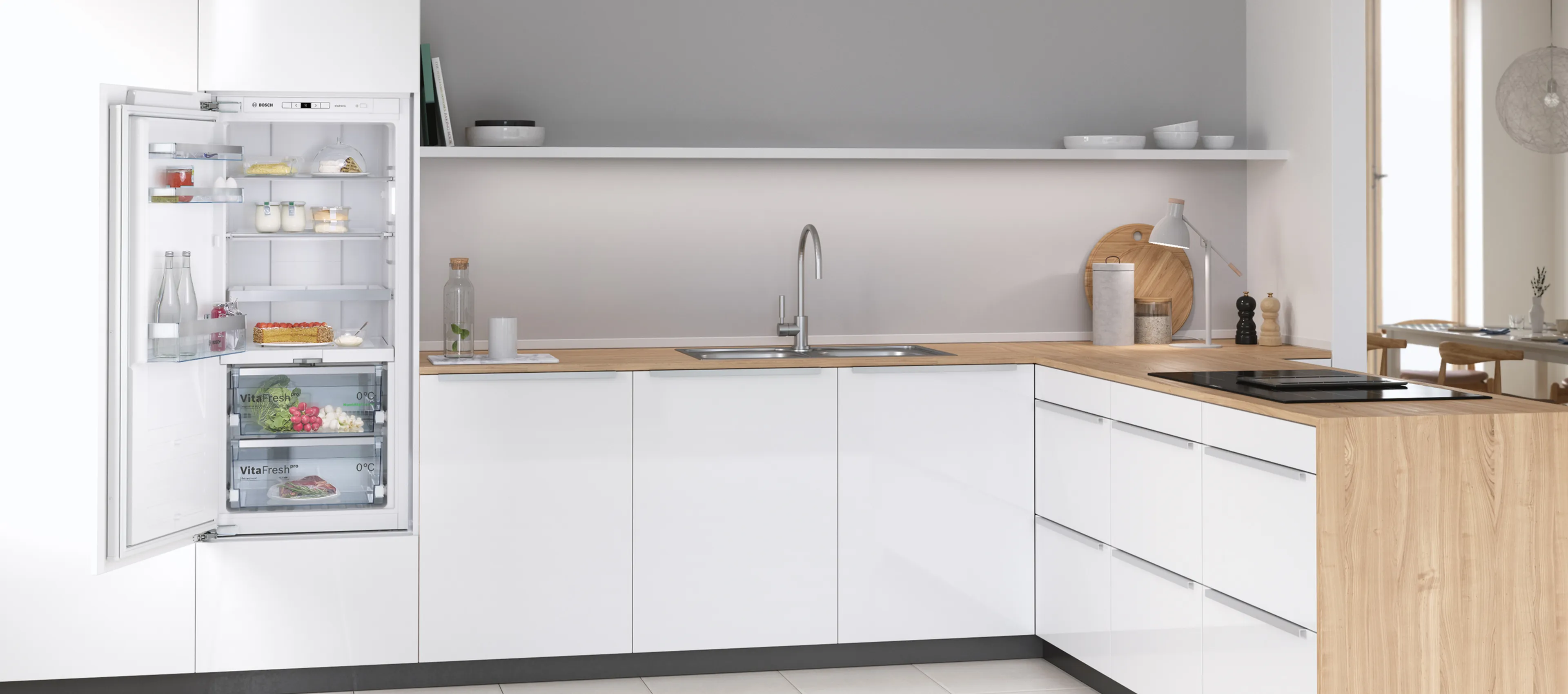 Modern kitchen with a white fridge and cabinets, wood counter, open fridge door, and a window.