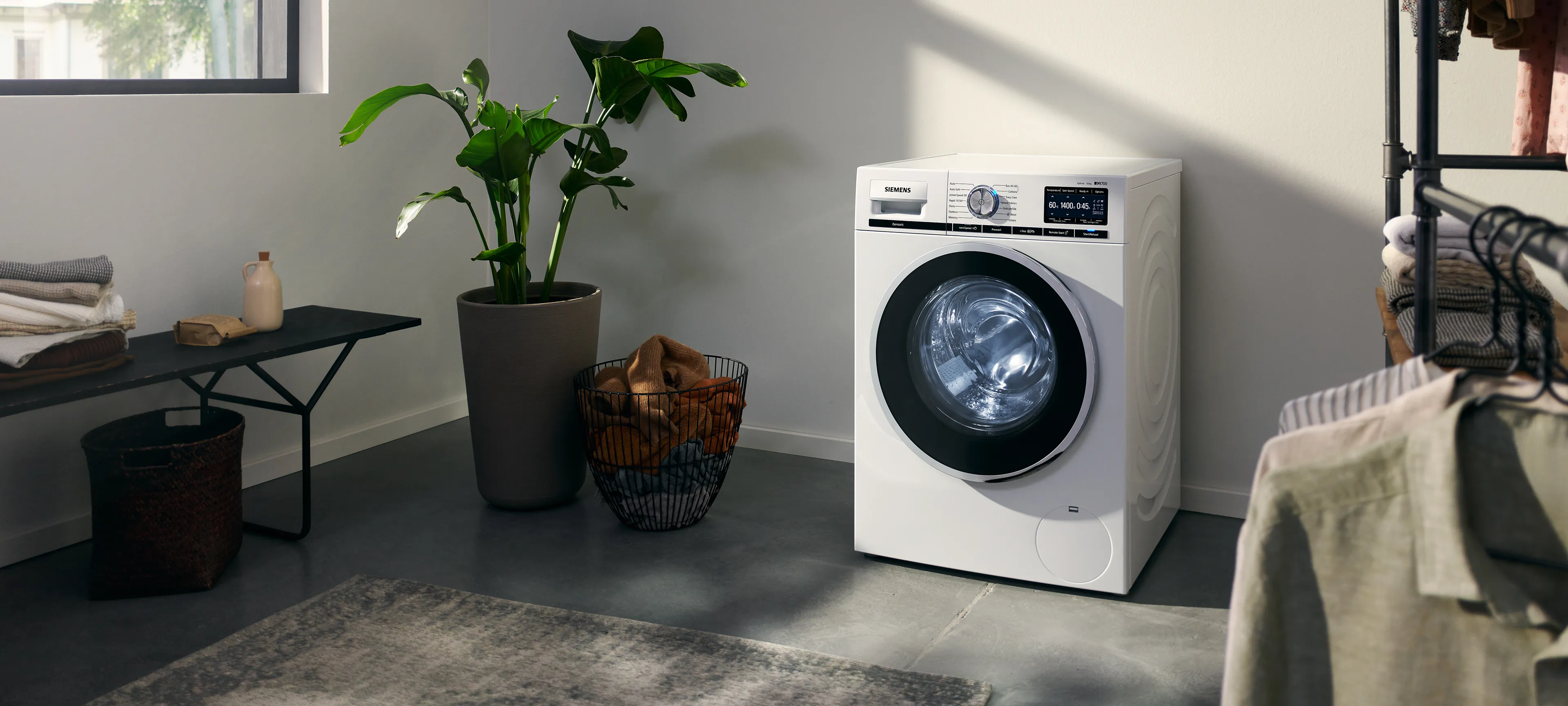 Modern laundry room with award-winning washer and dryer, shelves with towels, and clothes hanging.