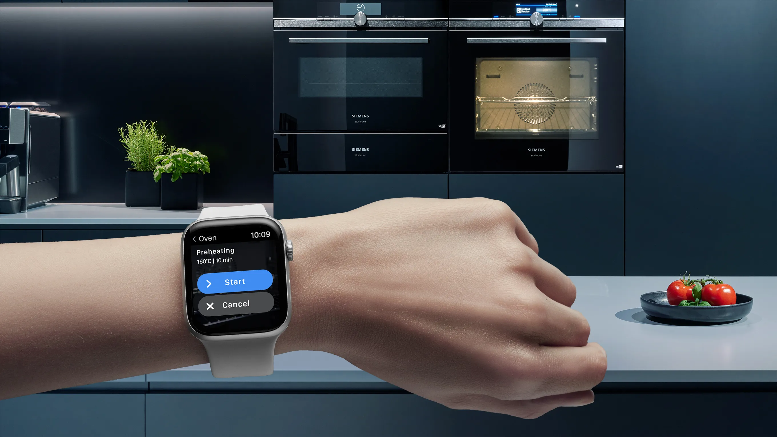 A person's arm wearing an Apple Watch displaying an oven control interface with 'Preheating 160°C | 10 min' and 'Start' and 'Cancel' buttons