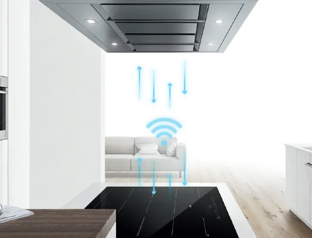 Ceiling-integrated kitchen hood communicating with a modern induction cooktop below via a blue Wi-Fi connectivity icon.