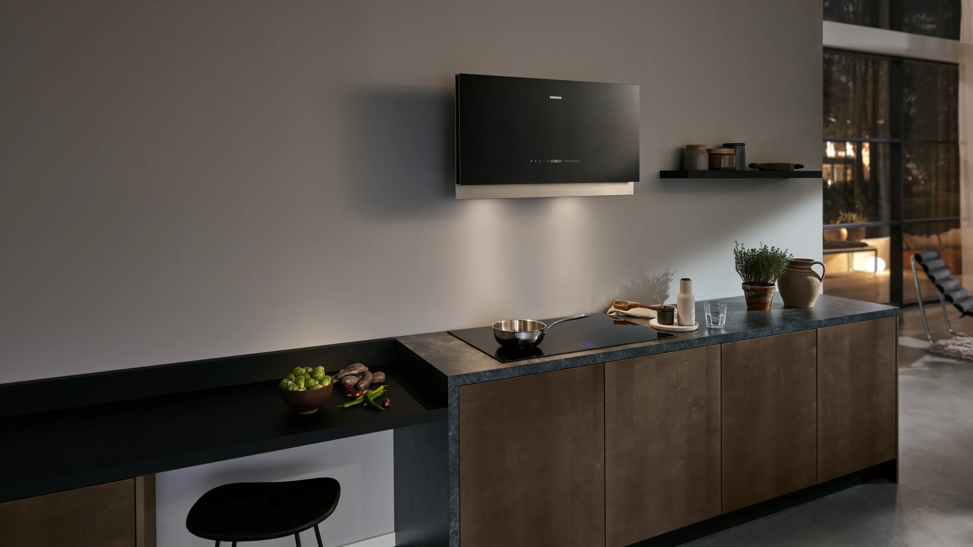 Siemens induction hob with integrated ventilation, steaming pan, and a modern dining setup in the background.