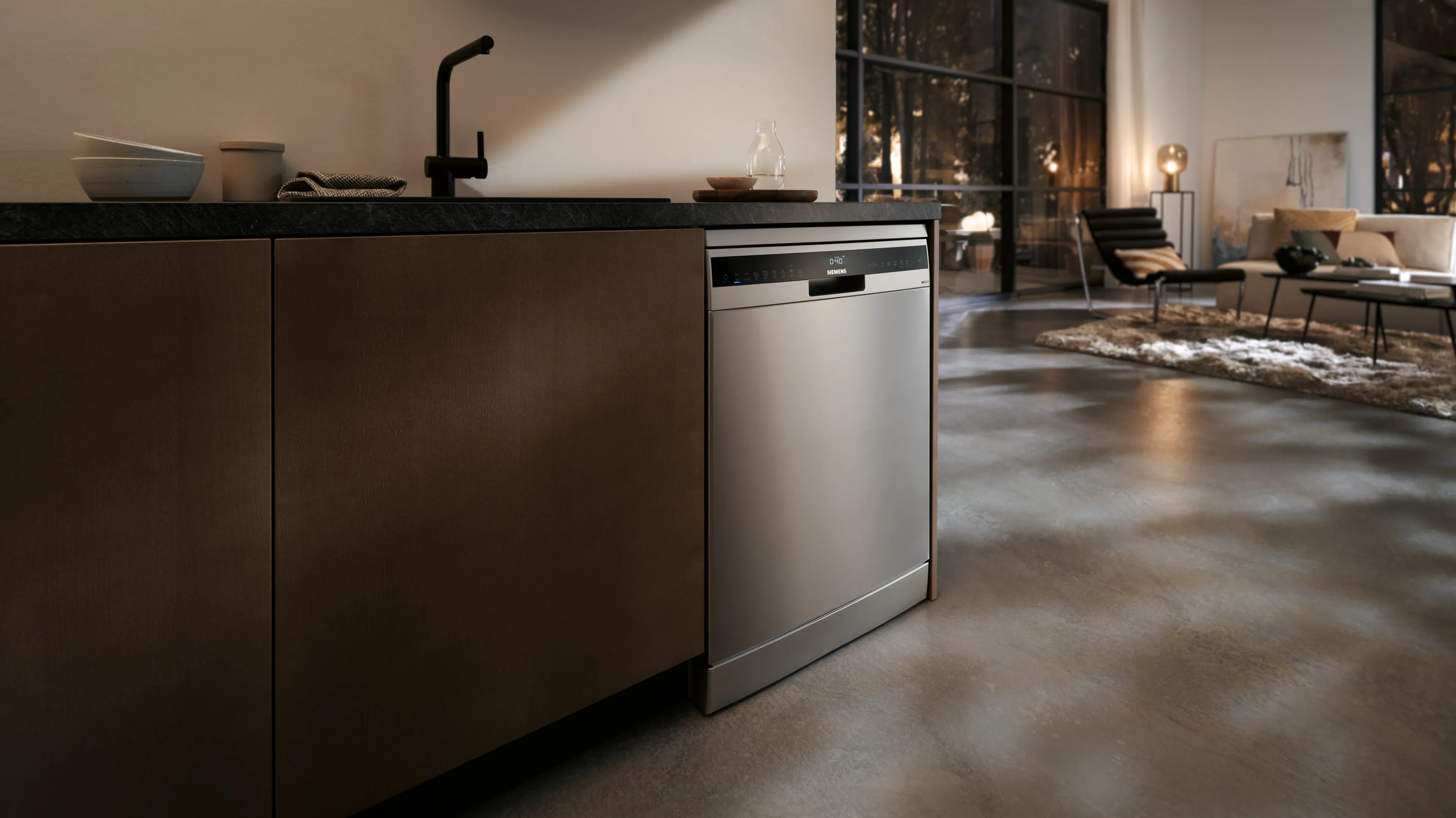 A modern kitchen featuring a sleek stainless steel dishwasher, dark cabinetry, and contemporary decor, illuminated by soft evening light.