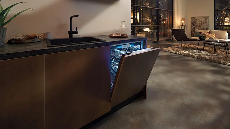Modern kitchen with dark countertop, sink, and open dishwasher revealing interior lights.
