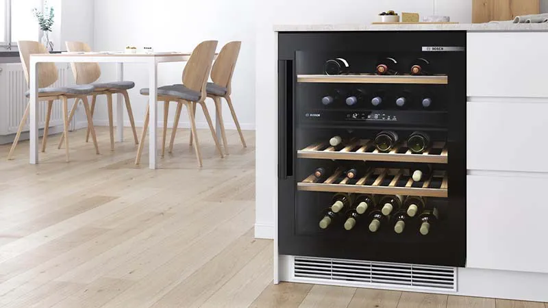 Cucina moderna con vino cooler, tavolo da pranzo e sedie in un interno luminoso e minimalista.