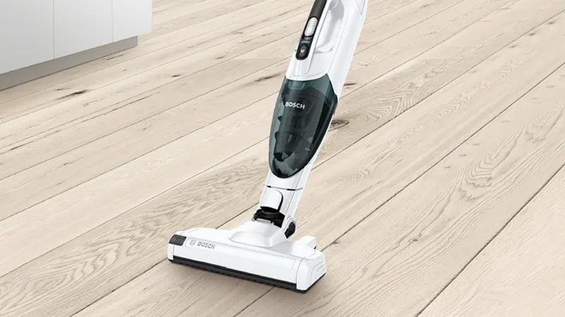 Cordless vacuum cleaner on hardwood floor, cleaning device with attachments, home cleaning equipment.