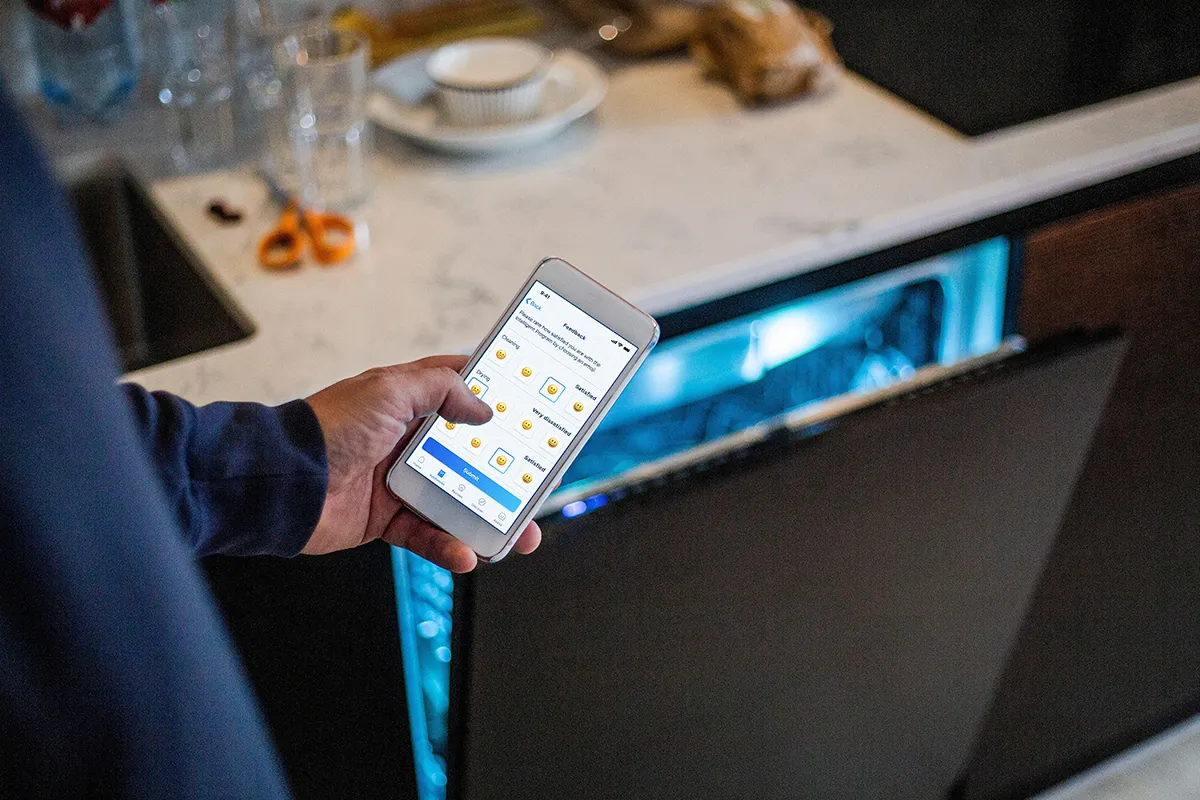 Person holding phone in front of open Bosch Dishwasher