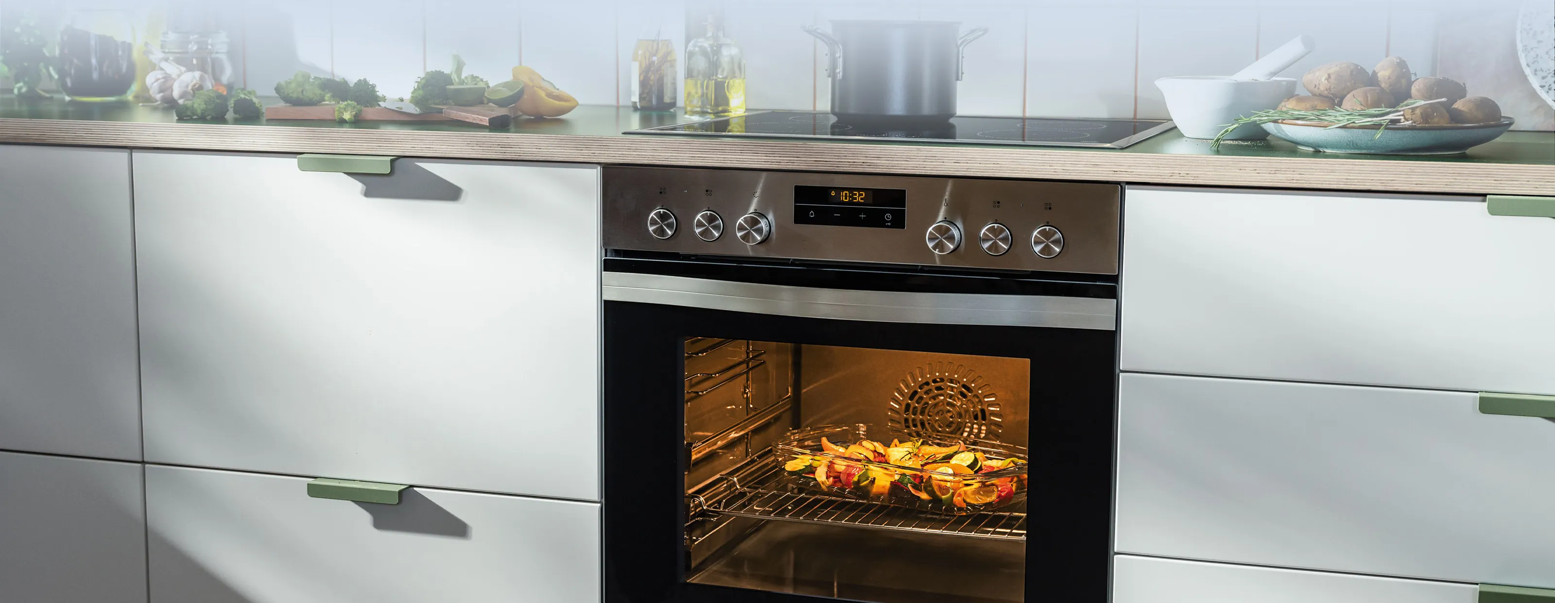 Eine moderne Küche mit einem Edelstahlofen, der geröstetes Gemüse zeigt, und einem Kochfeld mit Töpfen, das eine gemütliche Kochatmosphäre schafft.