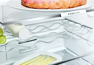 Bir plakada pişmiş bir yemek tabağı da dahil olmak üzere çeşitli gıda eşyaları ile açık buzdolabı.