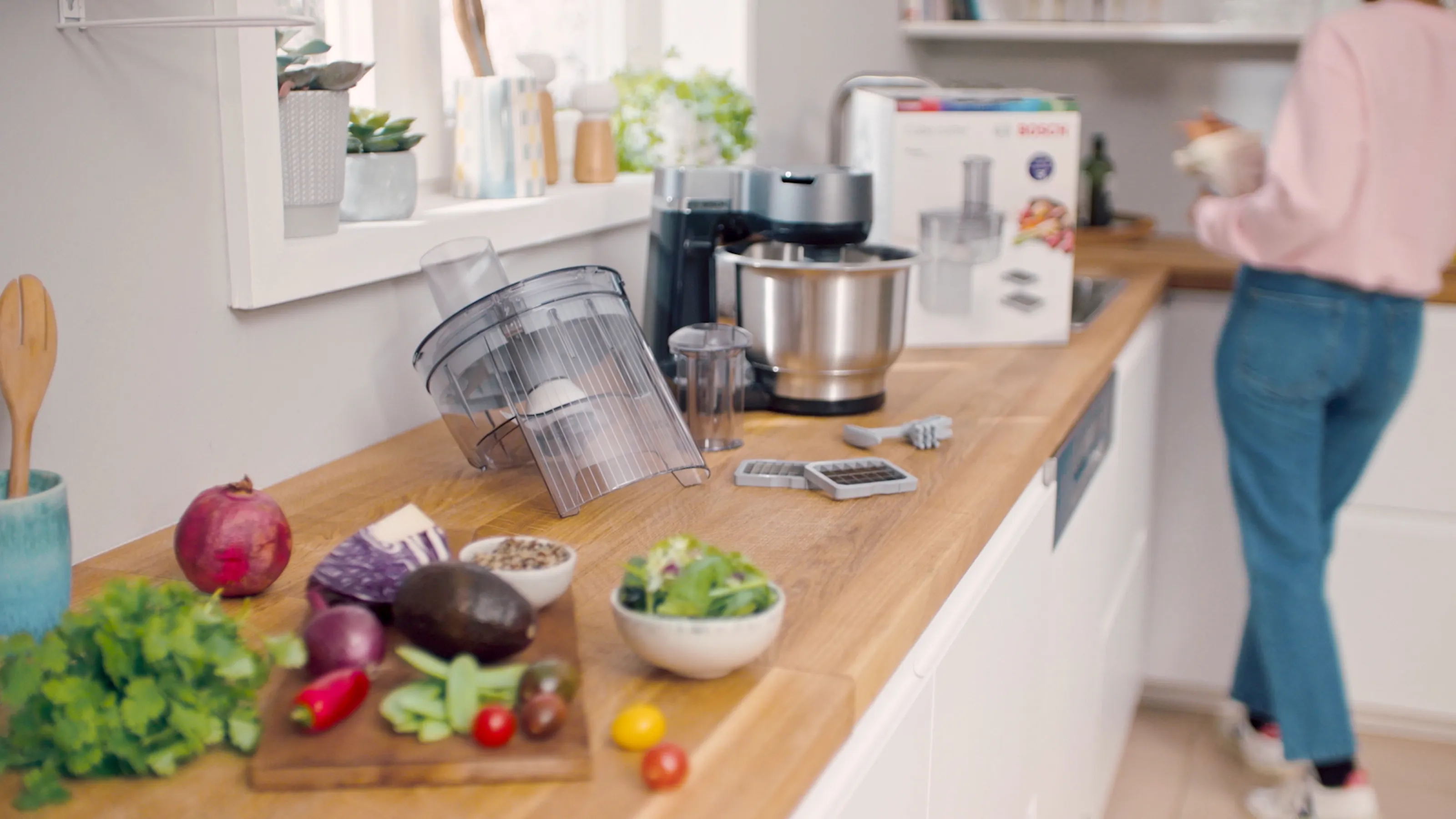 Kitchen counter with fresh produce, kitchen appliances, and a person in the background.