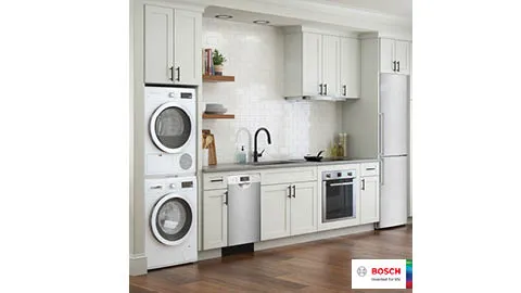 Modern kitchen with Bosch washer, dryer, dishwasher, oven, and refrigerator in white cabinets.