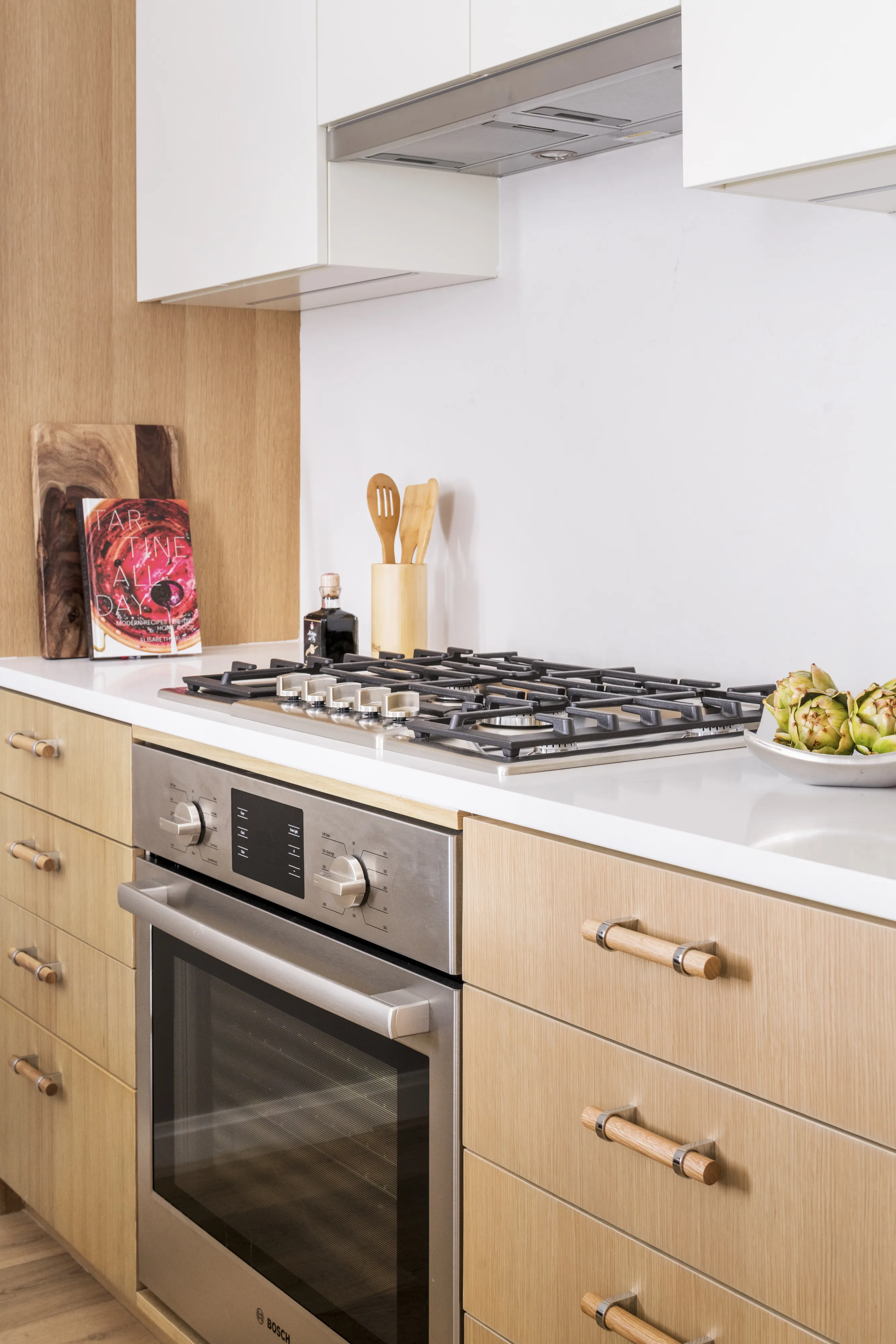 Modern kitchen with Bosch oven and stovetop, wooden cabinets, and countertop accessories.