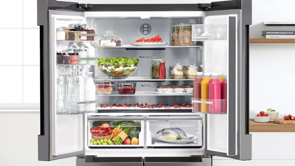 Open refrigerator filled with fresh produce, drinks, and various food items.