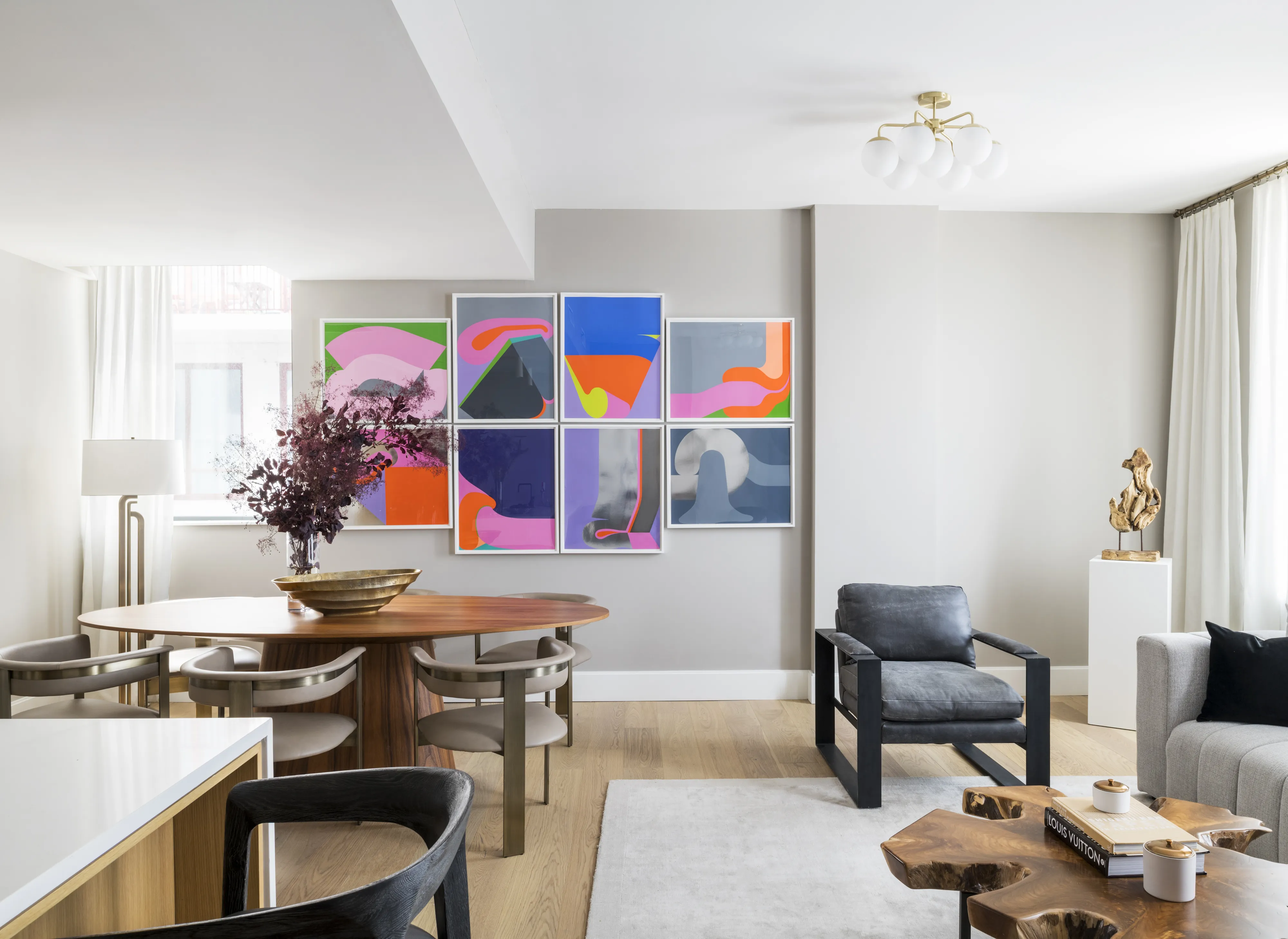 Modern living room with abstract art, dining table, and stylish furniture in neutral tones.