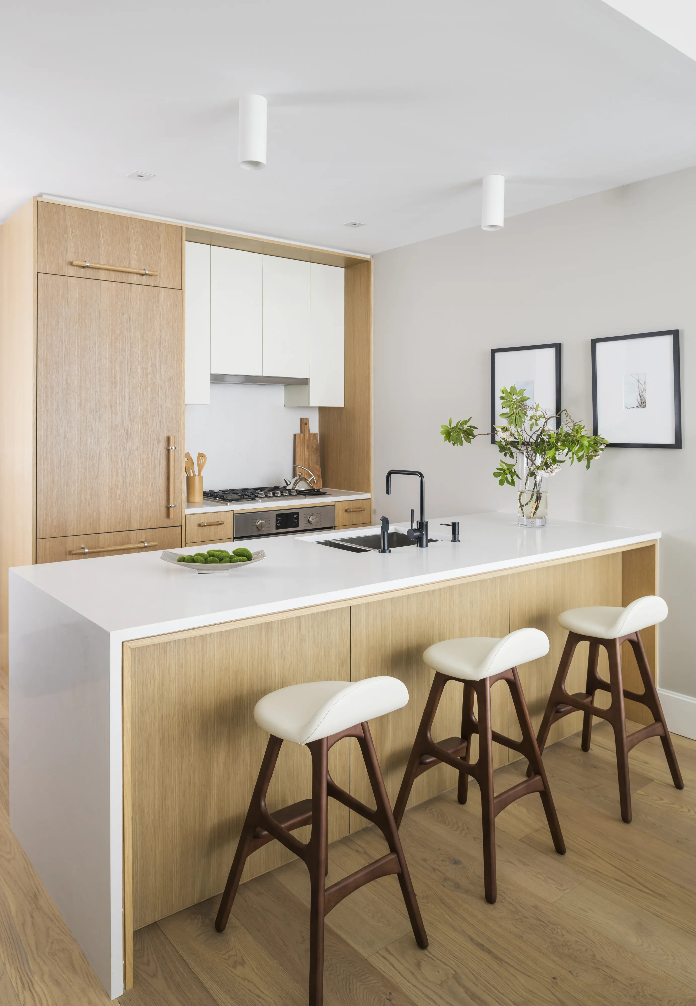 Modern kitchen with a Bosch gas range, white island, wooden bar stools, and minimalistic decor.