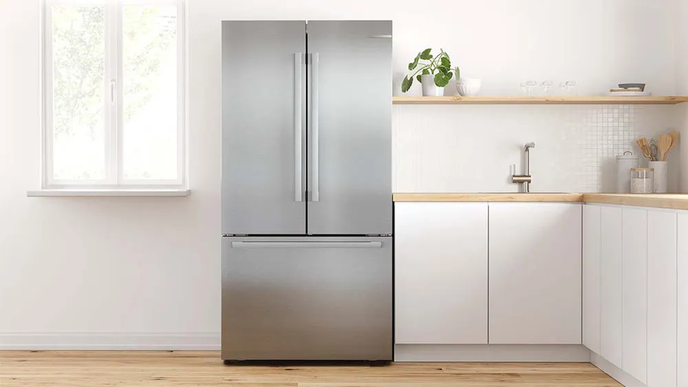 Modern kitchen with stainless steel refrigerator, wooden shelves, and white cabinets.