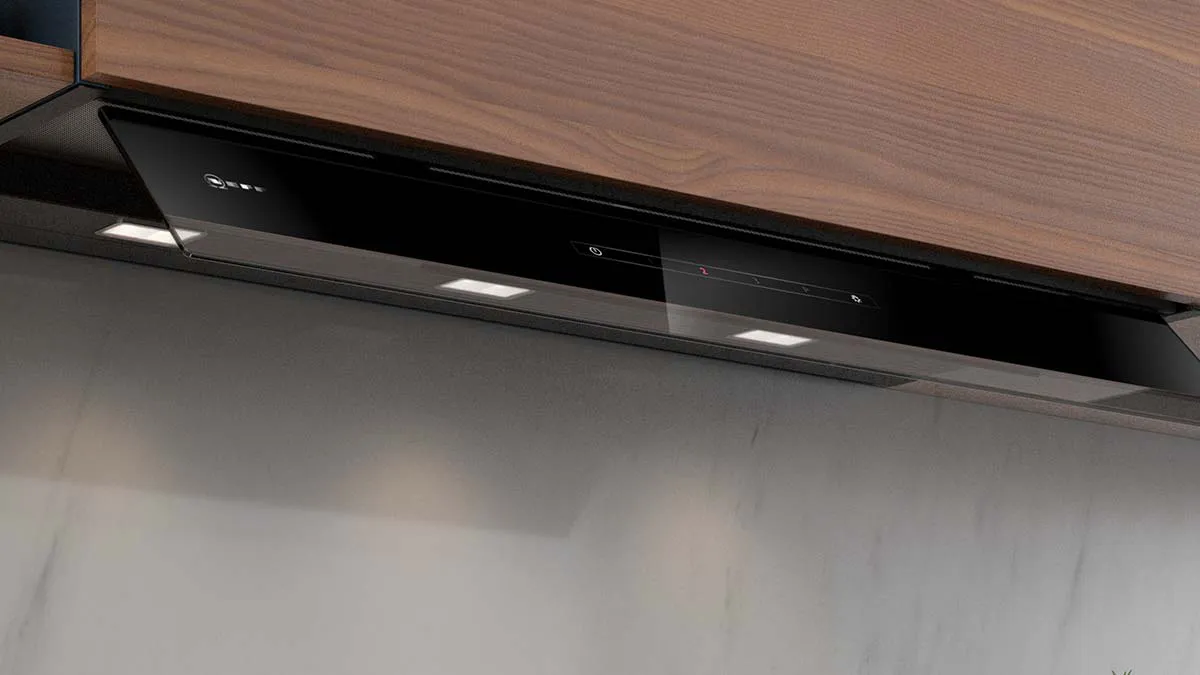 Ventilateur d'extracteur de cuisine noir monté au-dessus d'un dosseret carrelé blanc.