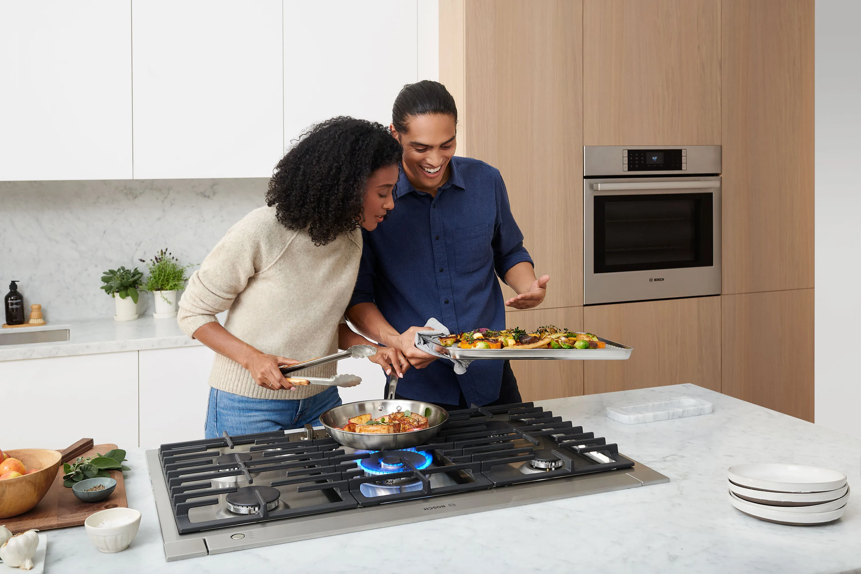 Man and woman cooking on a Bosch gas stove top inside a modern kitchen