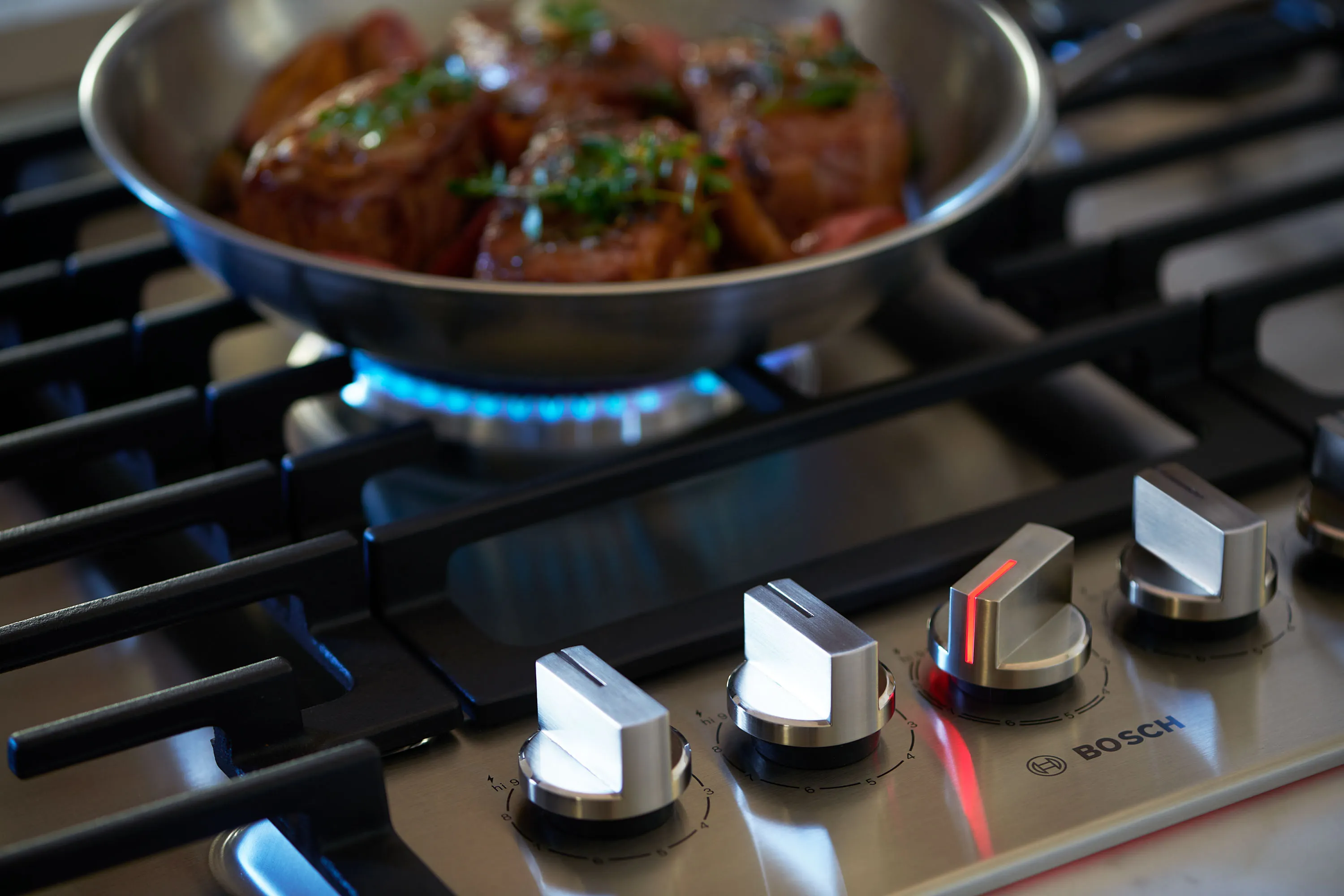 Pan cooking on a gas hob, showing control knobs