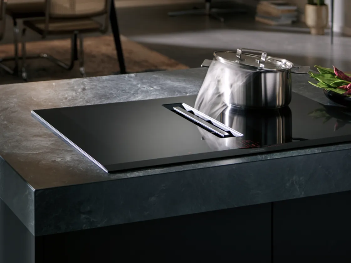 Modern kitchen countertop with induction cooktop, stainless steel pot, and minimalist design.