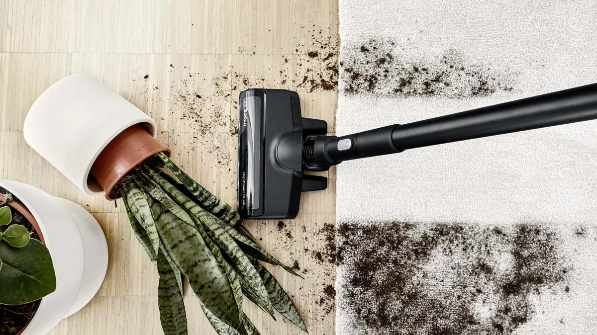 A high angle shot of a cordless vacuum cleaner drawn across three different surfaces that are covered in soil and other dry spills, leaving a perfectly clean trail in its wake.