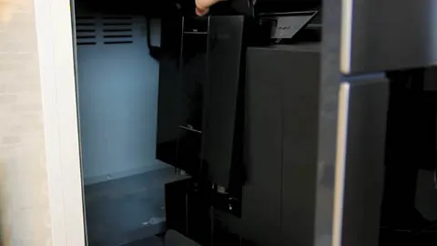 Interior view of a Bosch black built-in coffee machine with open doors and visible cooling vents.