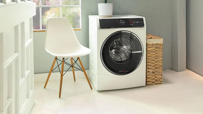 Moderne Waschküche mit Waschtrockner, Stuhl und Korb.