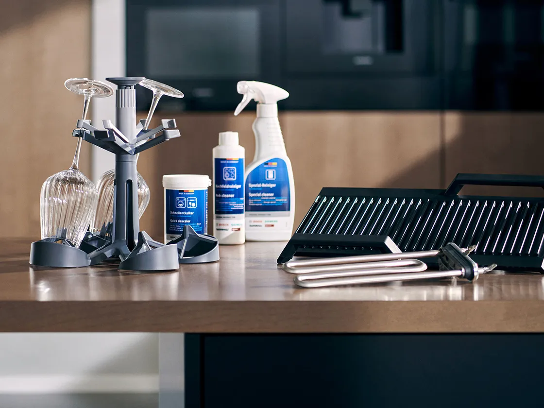 Сцена на плот, включваща почистващи средства, стойка за сушене на чаши и винени чаши, показваща съвременна кухня.