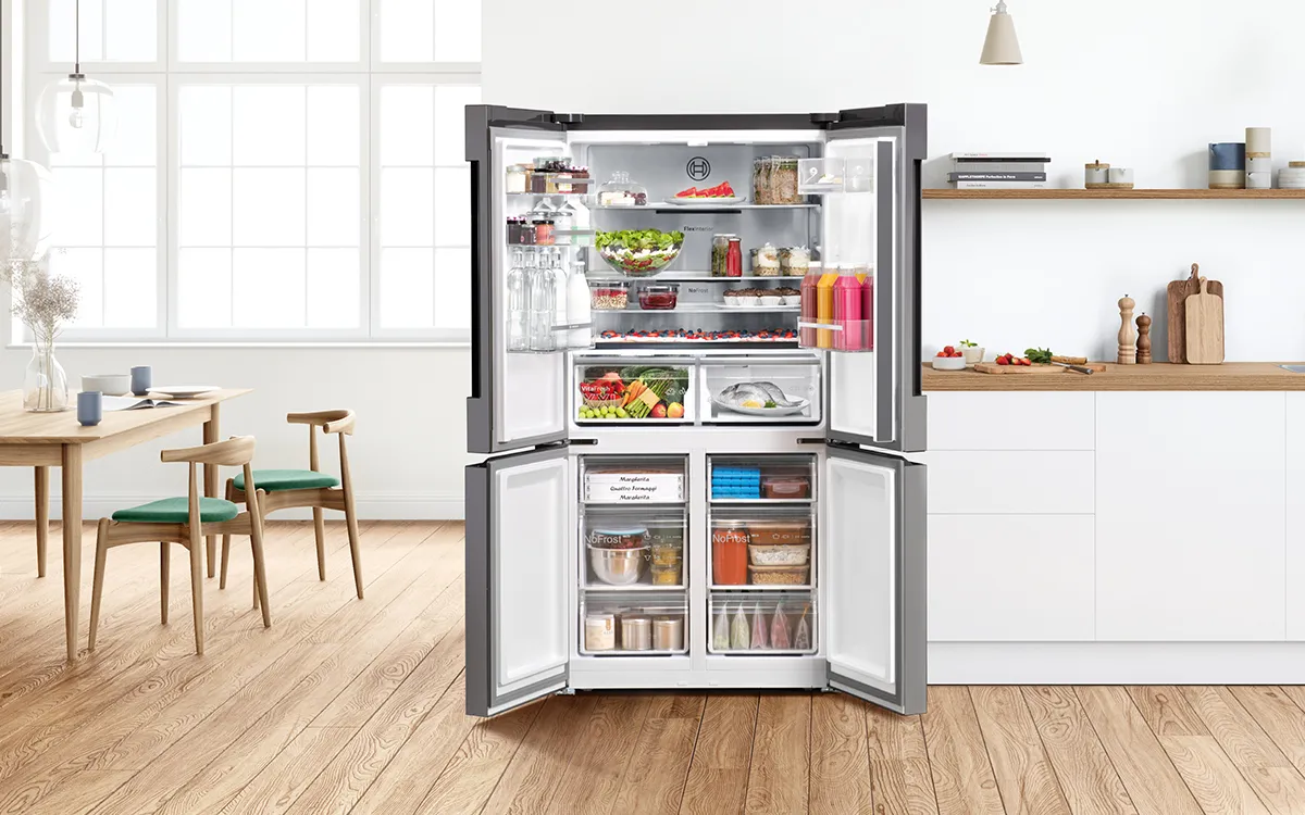 Cuisine moderne avec réfrigérateur ouvert contenant divers aliments et accessoires de cuisine.