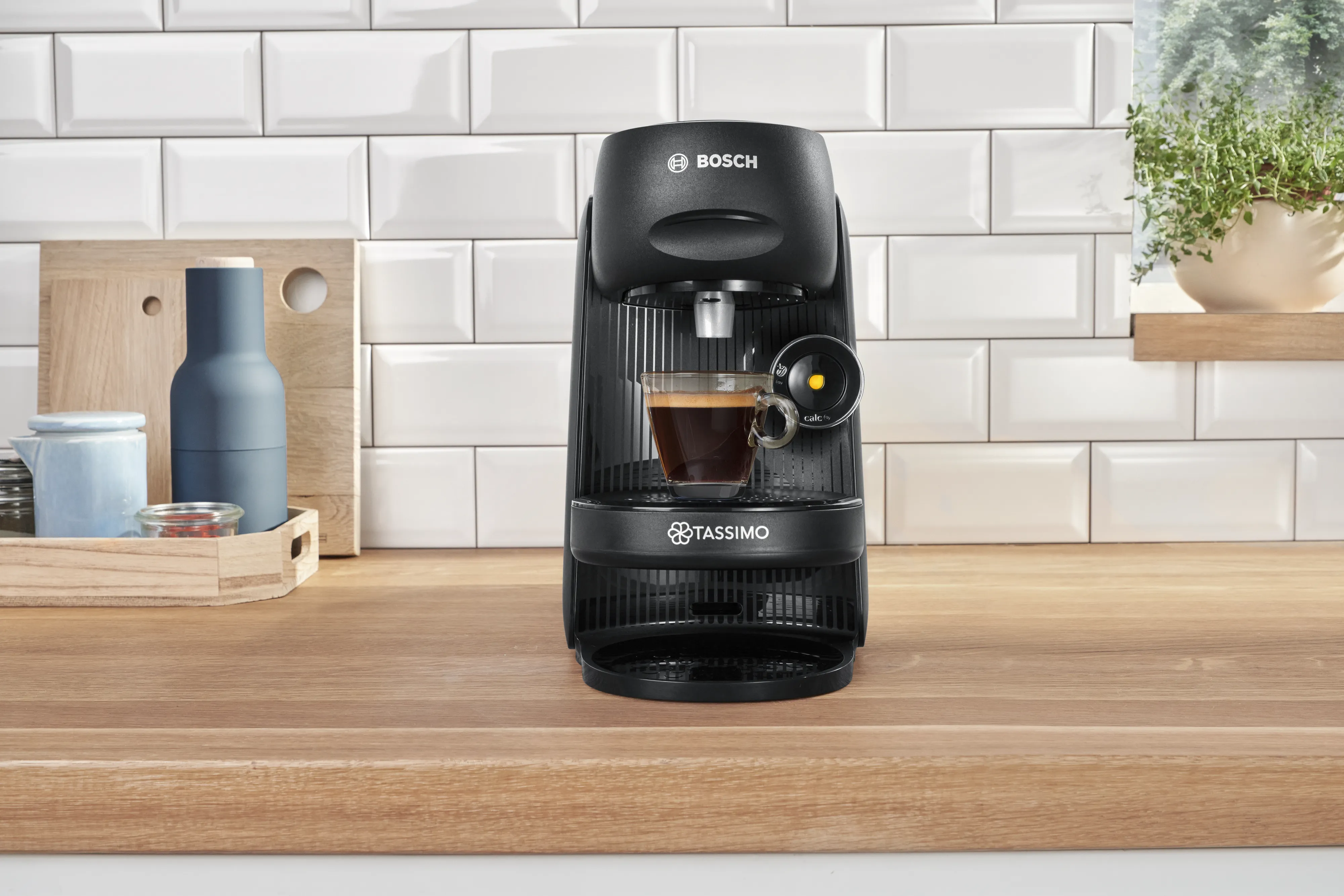Aparatul de cafea TASSIMO FINESSE cu o ceașcă de espresso plină, pe un blat de bucătărie.